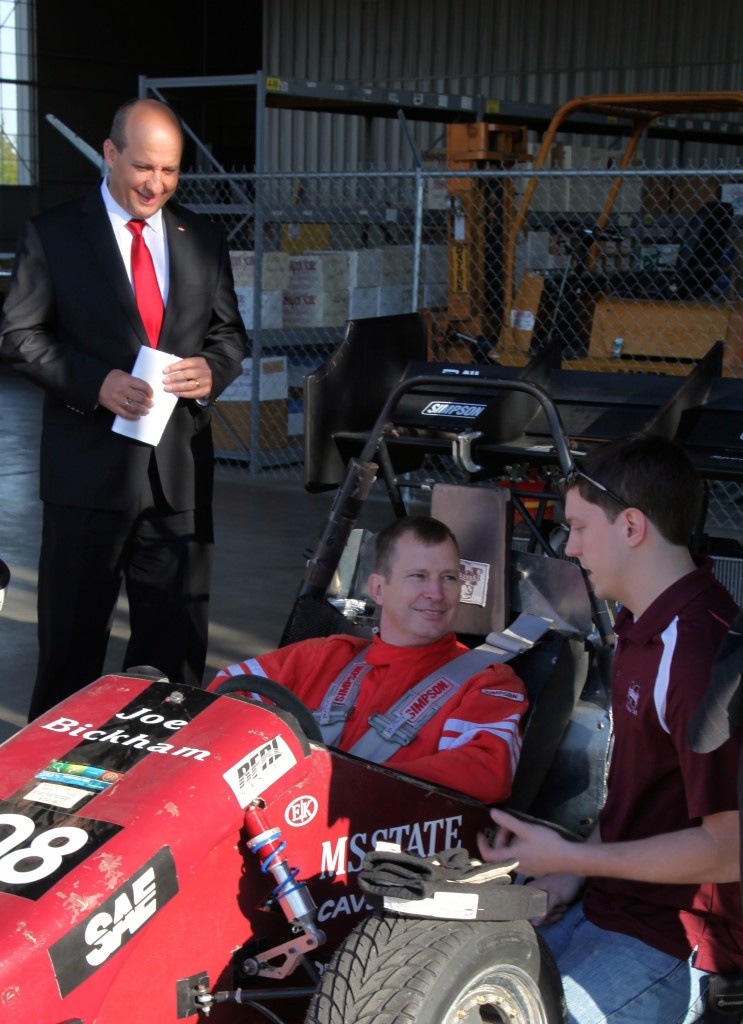 Do Val looks on while Dow's Richard Rolke receives instruction on driving MSU's formula racing car from team leader Dash Robinson